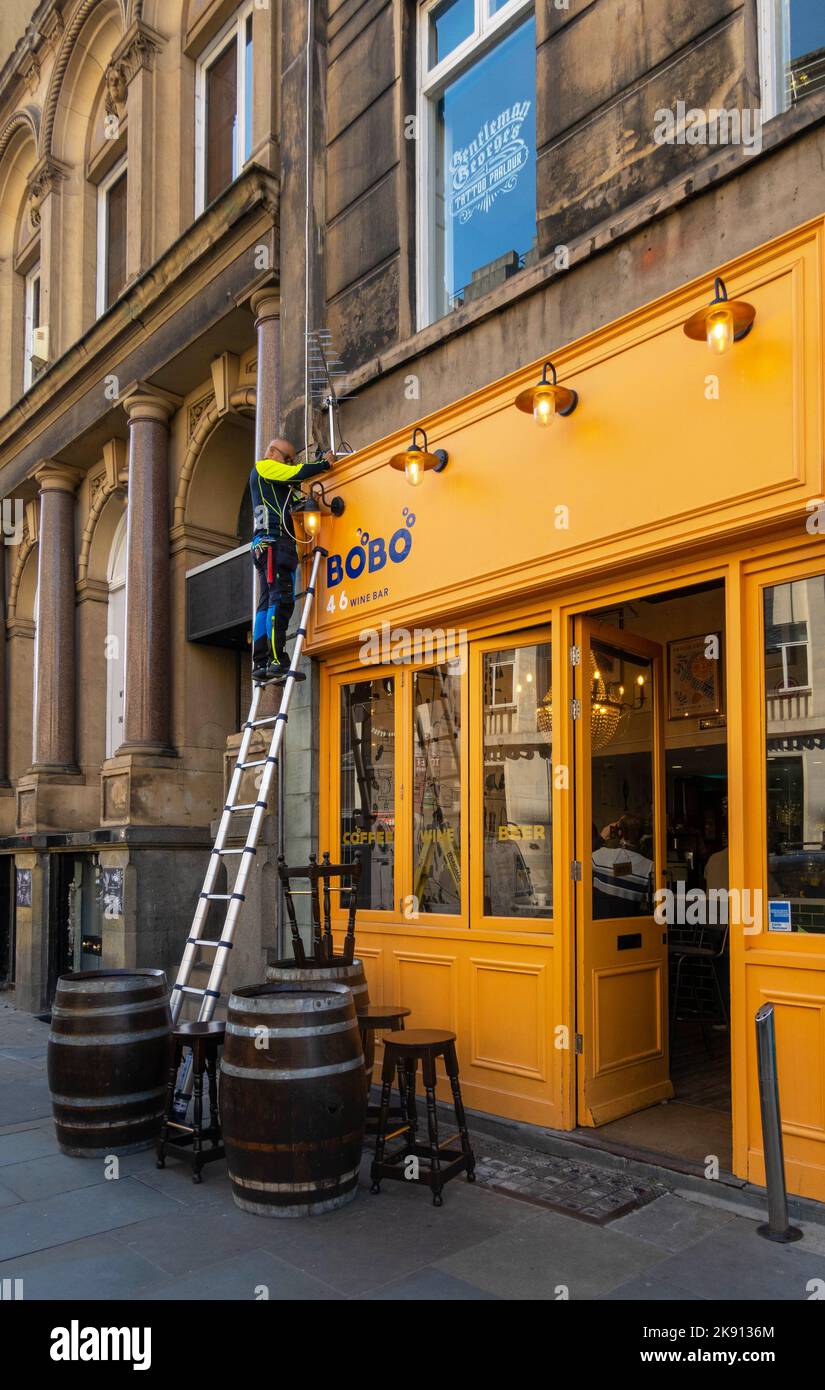 Travailleur sur une échelle réparant un système électrique dans un restaurant bar de Castle Street Liverpool Banque D'Images