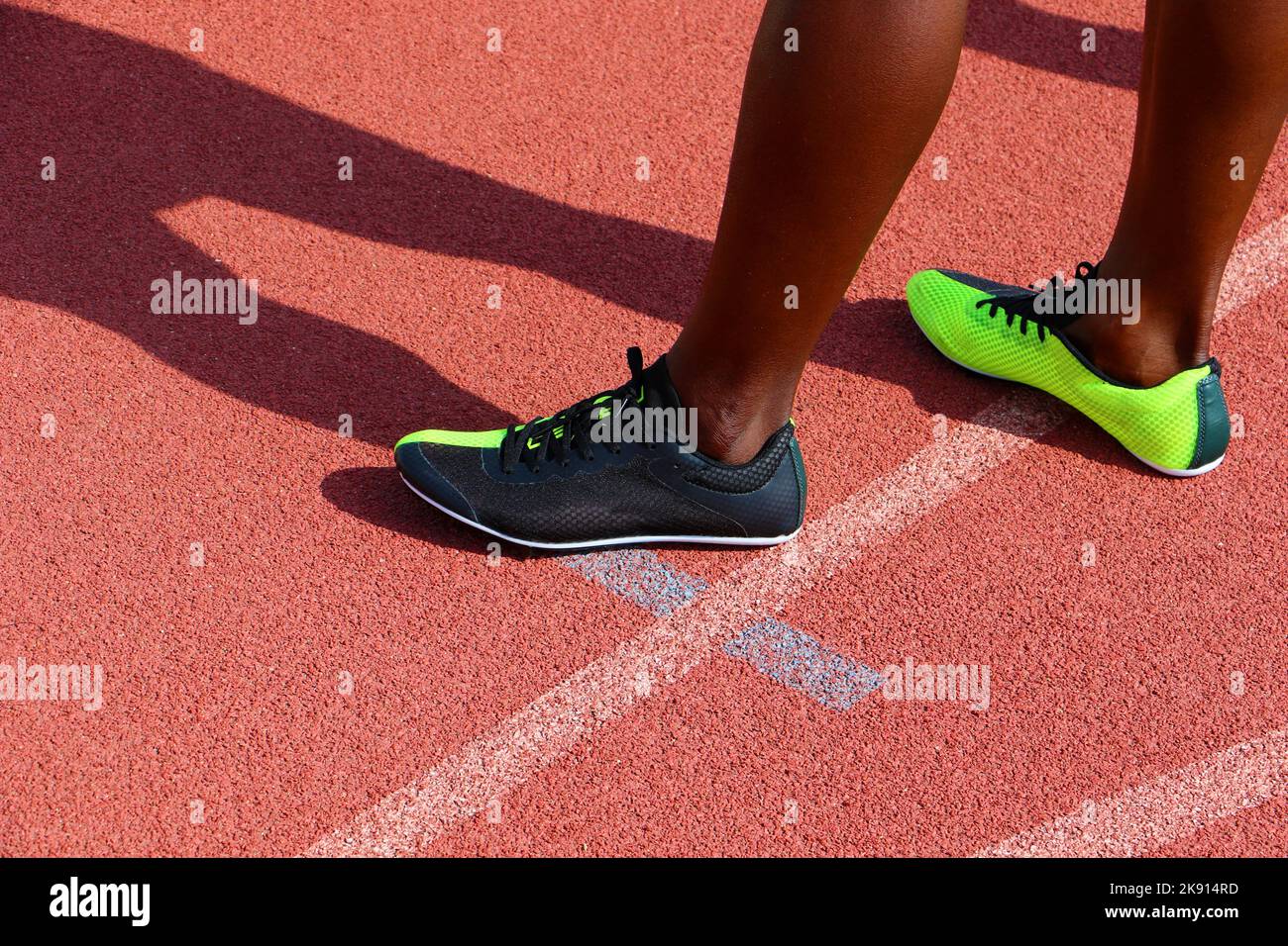 Pieds de sprinters portant des chaussures de course debout sur une piste d'athlétisme Banque D'Images