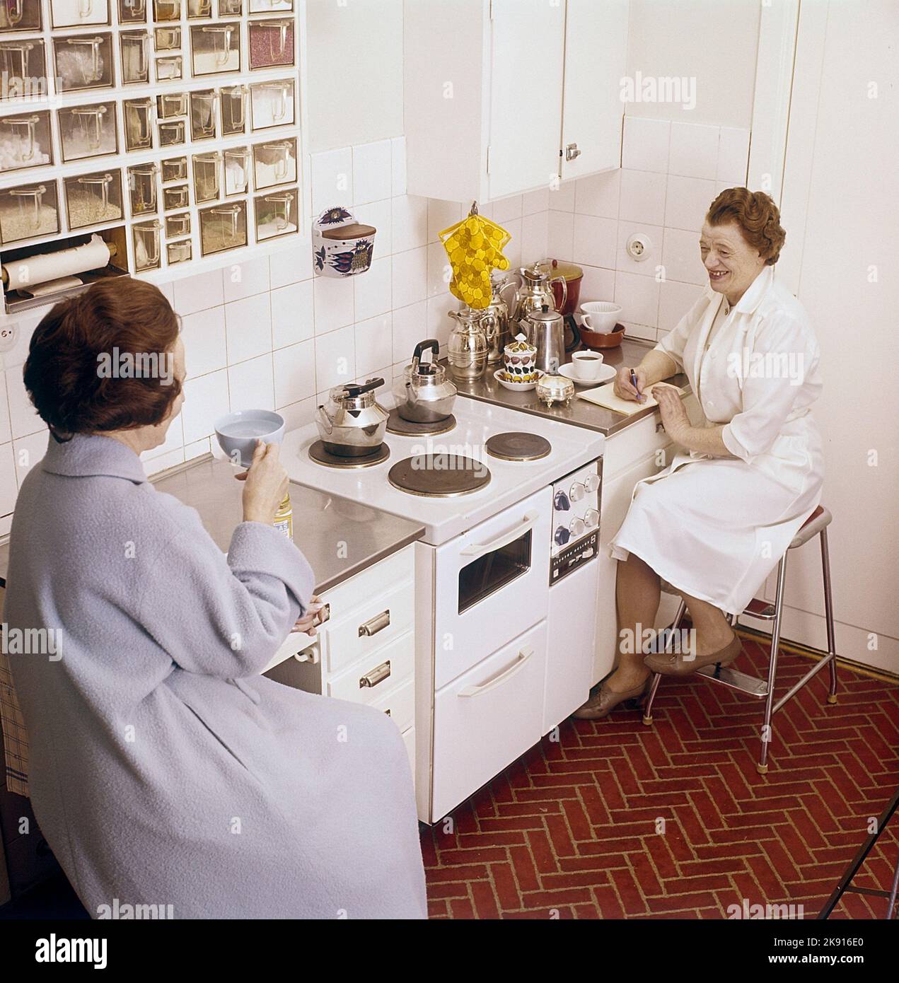 Dans la cuisine 1960s. Intérieur d'une cuisine et deux femmes ayant du thé et du café. Suède 1962 réf. CV83 Banque D'Images