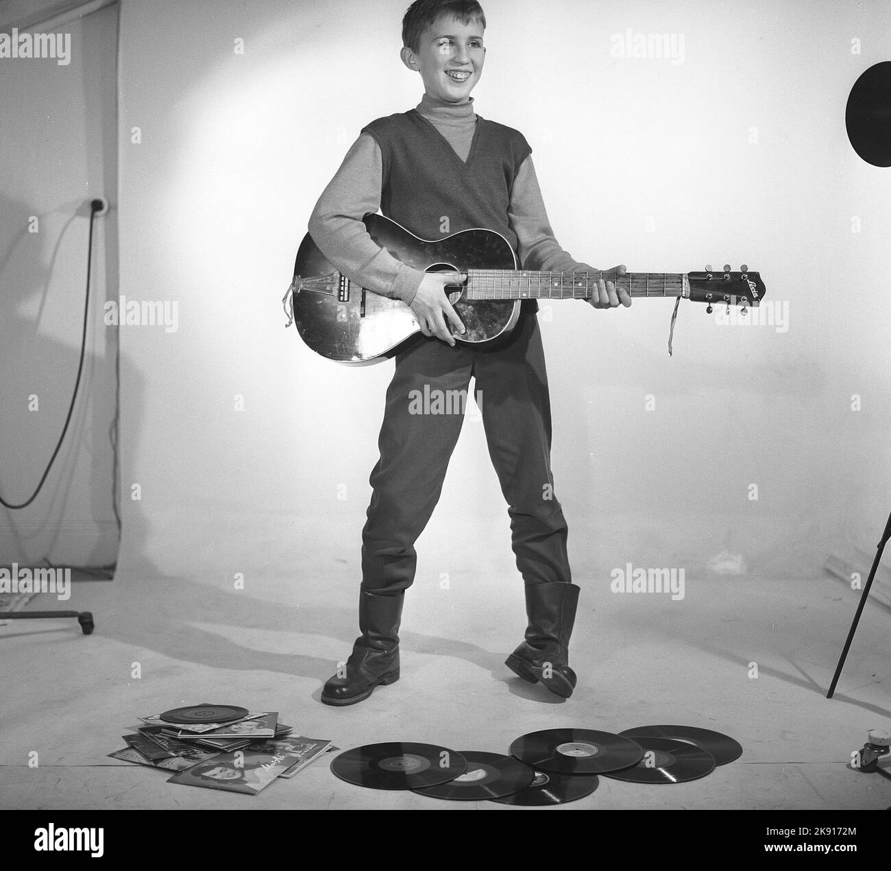 Garçon dans les 1950s. Un garçon est photographié dans un studio et joue de la guitare, peut-être avec les artistes Rock n' roll de l'époque à l'esprit. Suède 1959 Kristoffersson réf. CF62 Banque D'Images