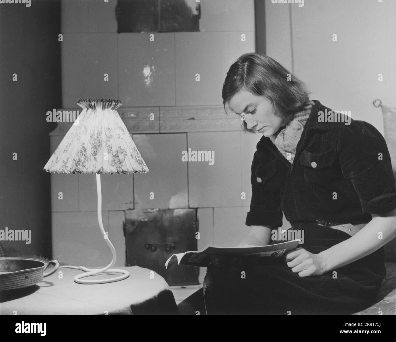 Femme dans les 1950s. Une jeune femme aux cheveux sombres à la maison lisant un magazine. Suède 1950 Banque D'Images