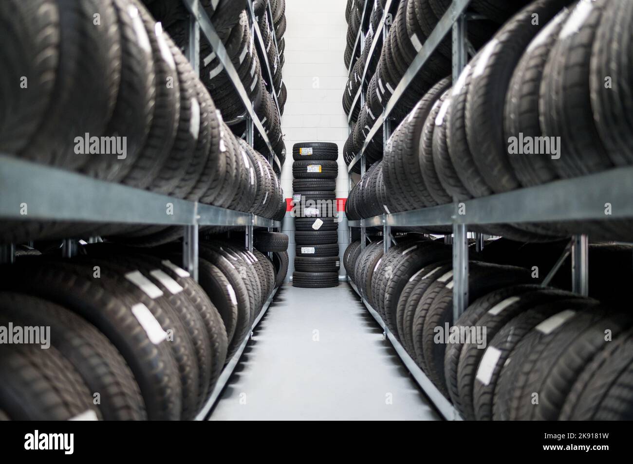 Perspective rangée de tablettes de pile avec les nouveaux pneus disposés dans la salle de service de voiture du magasin Banque D'Images
