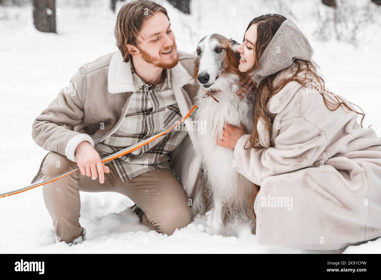 Amour romantique jeune couple fille, gars dans neige froid forêt d'hiver marchant avec animal, chien de chasse race russe borzoi. Sighthound, propriétaire de wolfdrier. H Banque D'Images