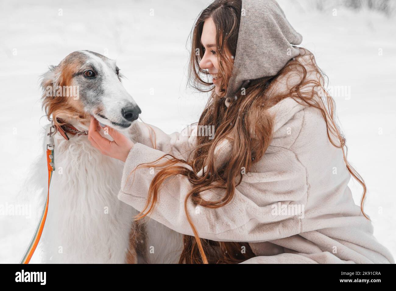 Jeune belle fille dans neige froid hiver gel forêt marchant avec animal de compagnie, chien de chasse race russe borzoi. Sighthound, propriétaire de wolfdrier. S'amuser, Banque D'Images