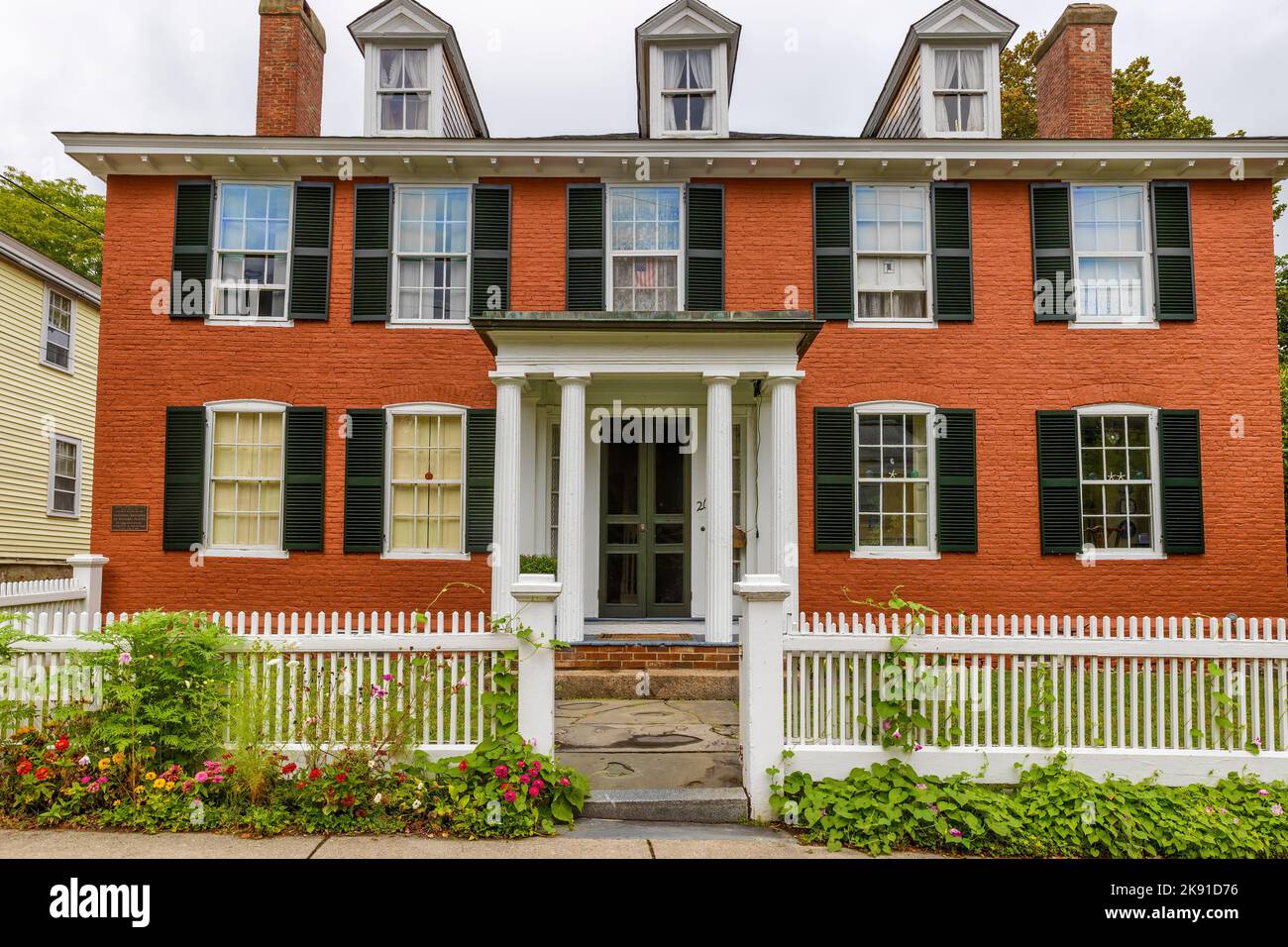Plymouth, Massachusetts, Etats-Unis - 12 septembre 2022: Maison en brique rouge avec volets noirs et clôture blanche. Banque D'Images