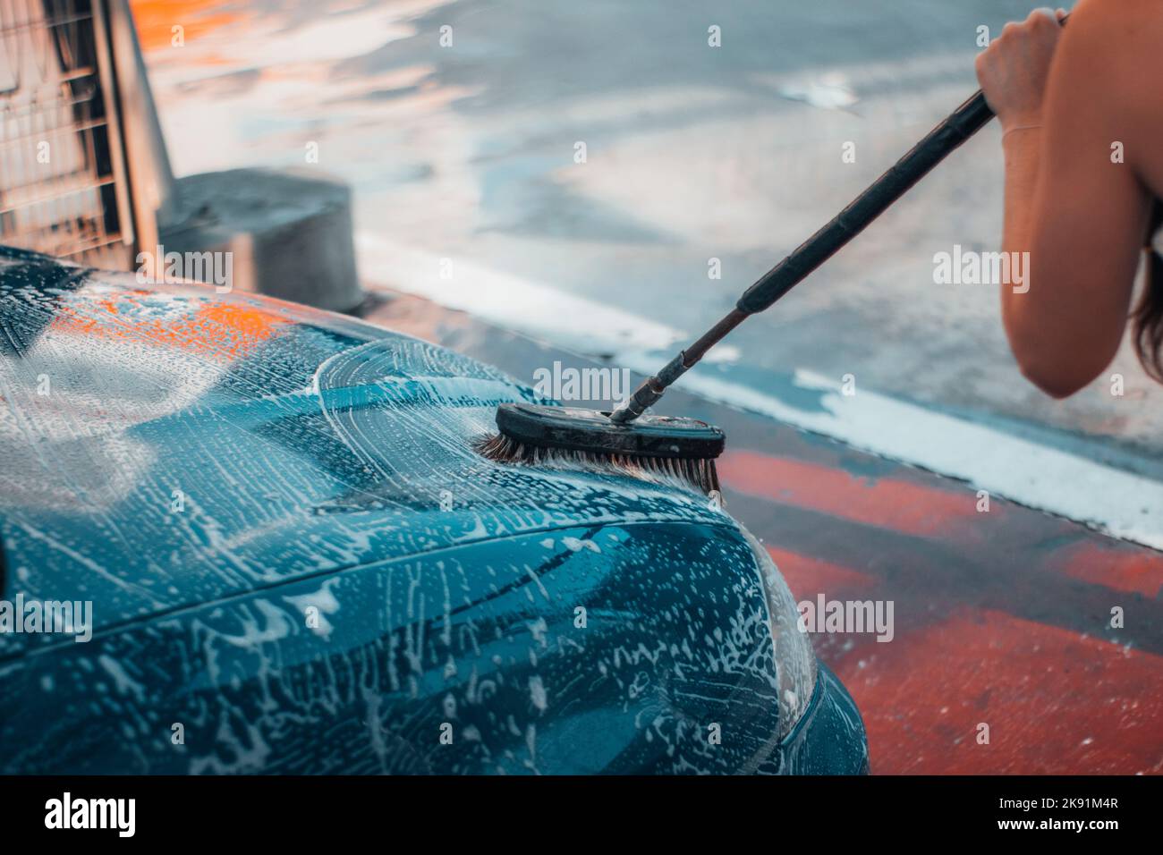 Un gros plan de la fille lavant une voiture avec une brosse dans le lavage automatique. Banque D'Images