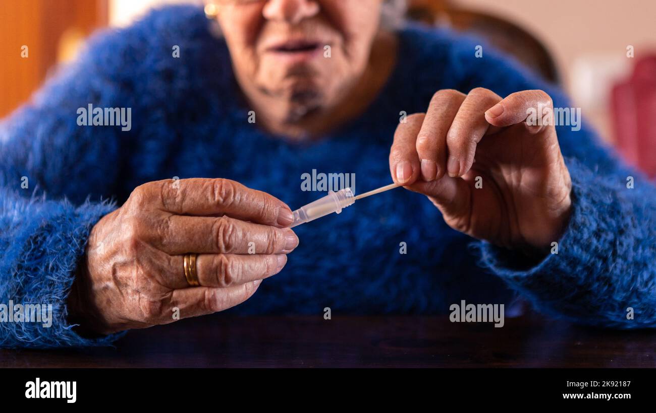 Gros plan de la femme âgée qui a effectué un auto-test à domicile pour Covid19 avec un kit d'antigène. Grand-mère caucasien introduisant un bâton nasal à un compte-gouttes tampon pour Banque D'Images