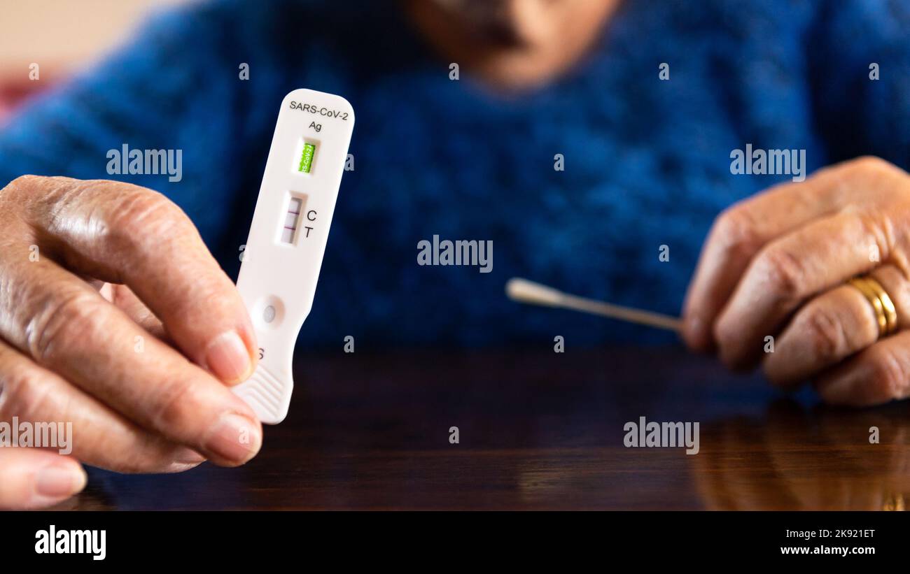 Le grand-mère caucasien fabrique un dispositif de test rapide à domicile pour le virus Covid19 avec un résultat positif. Grand-mère utilisant une cassette antigène de PCR express test f Banque D'Images