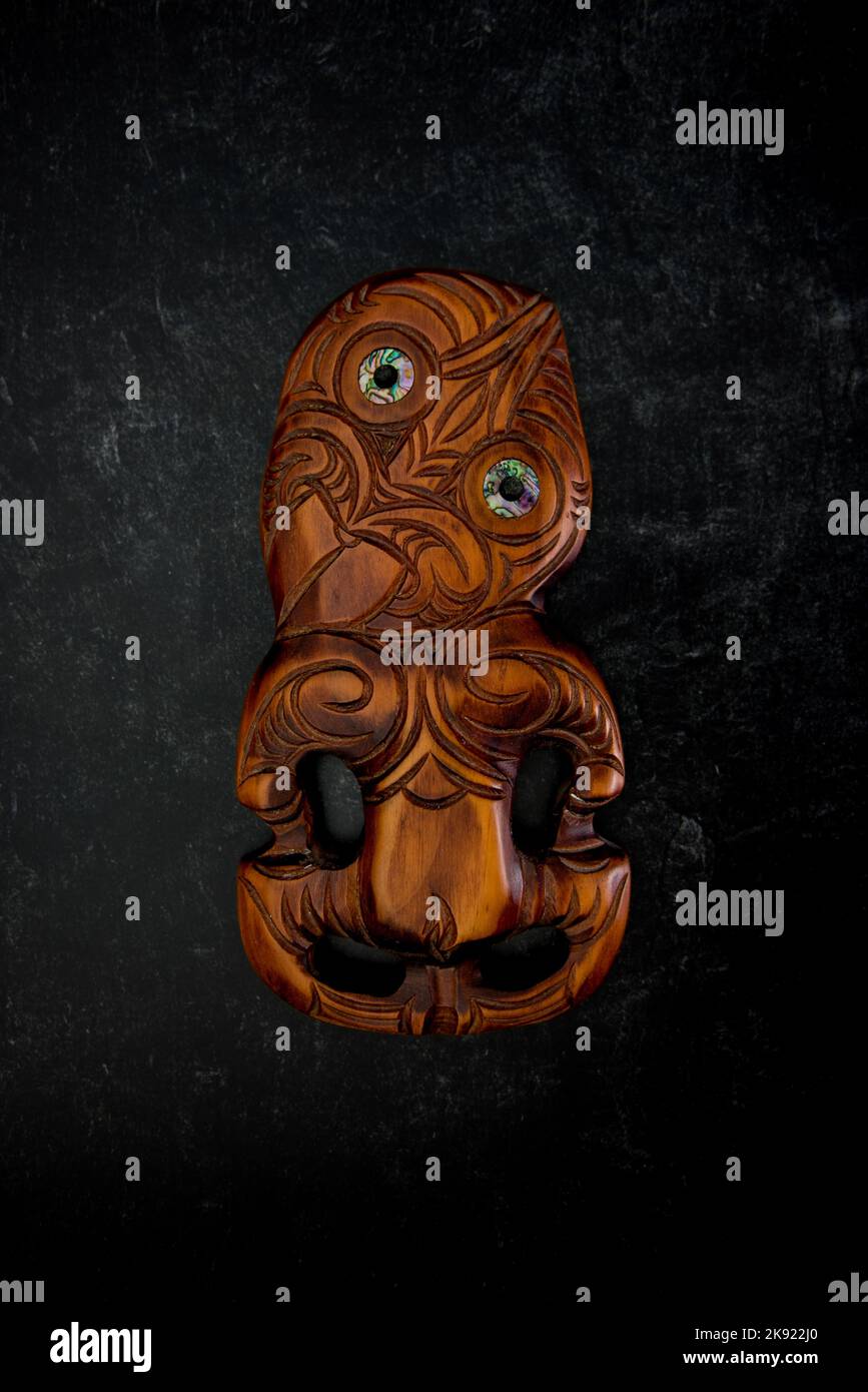 Hei Tiki en bois maori sculpté à la main avec des yeux de coquillages de paua. Taonga de Nouvelle-Zélande. Banque D'Images
