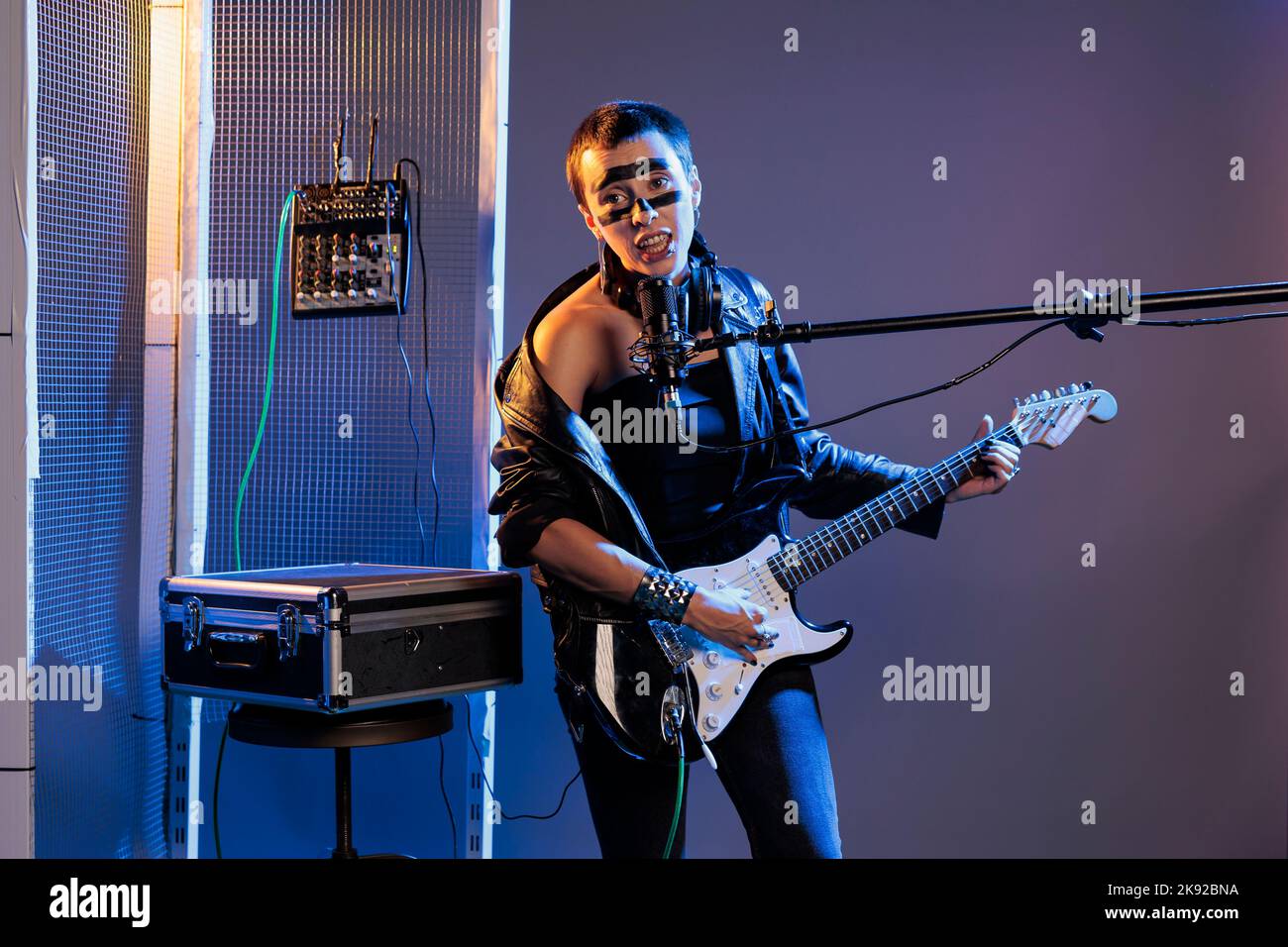 Cool alternative rock guitariste jouant en studio avec des lumières sombres et de la fumée, jouant de la guitare électrique et chantant heaby Metal Song. Faire de la musique avec l'installation et le microphone, artiste amusant. Banque D'Images