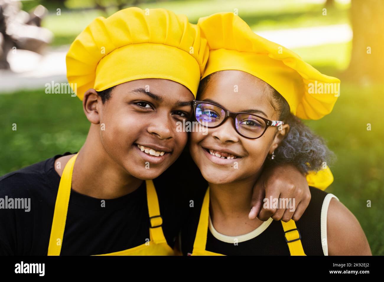 Les enfants africains cuisinent dans les chefs chapeau et uniformes jaunes  souriant portrait de près . L'adolescent africain et la fille noire ont du  plaisir et cuisent la nourriture Photo Stock -