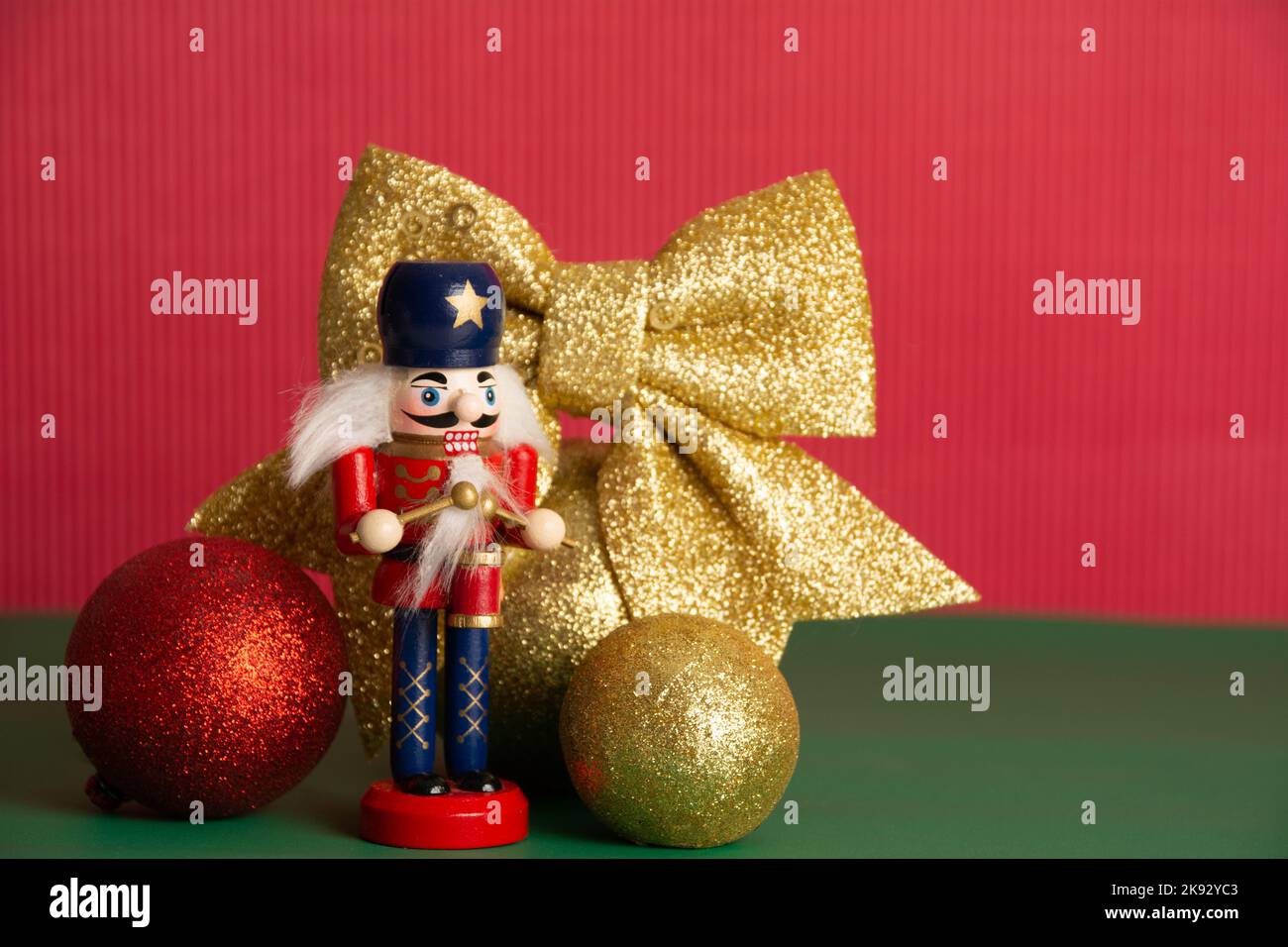 Poupée casse-noisette, boules de Noël dorées et rouges, ruban, fond rouge, décoration. Carte, espace de copie. Bonne Année. Vacances d'hiver. Maquette. Copie s Banque D'Images