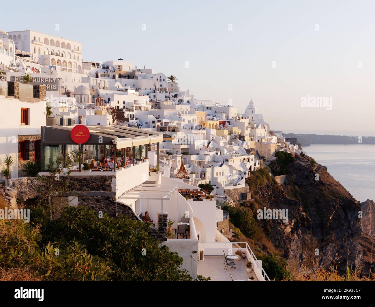 Ville de Fira en soirée avec restaurant en premier plan. Île grecque des Cyclades de Santorin dans la mer Égée Banque D'Images