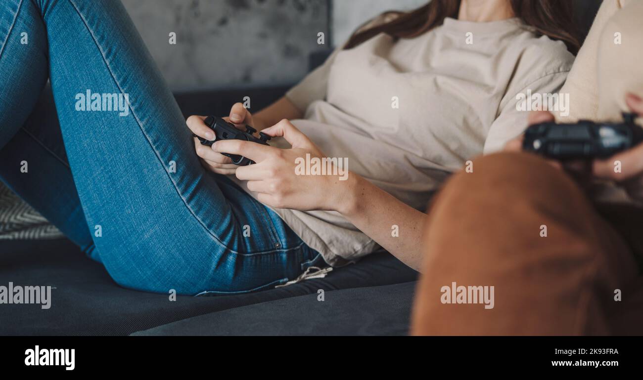 Les mains de deux femmes jouant à un jeu d'ordinateur s'amusant ensemble. Accro au jeu vidéo. Gadget de divertissement moderne. Joueurs aux cheveux gris. Banque D'Images