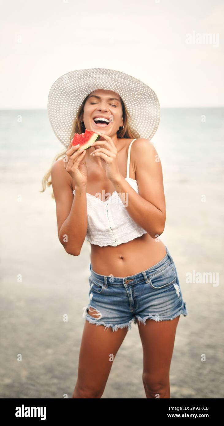 Rien n'est plus unique... la pastèque par temps chaud. Une jeune femme attrayante debout et jouée d'un morceau de pastèque pendant ses vacances. Banque D'Images