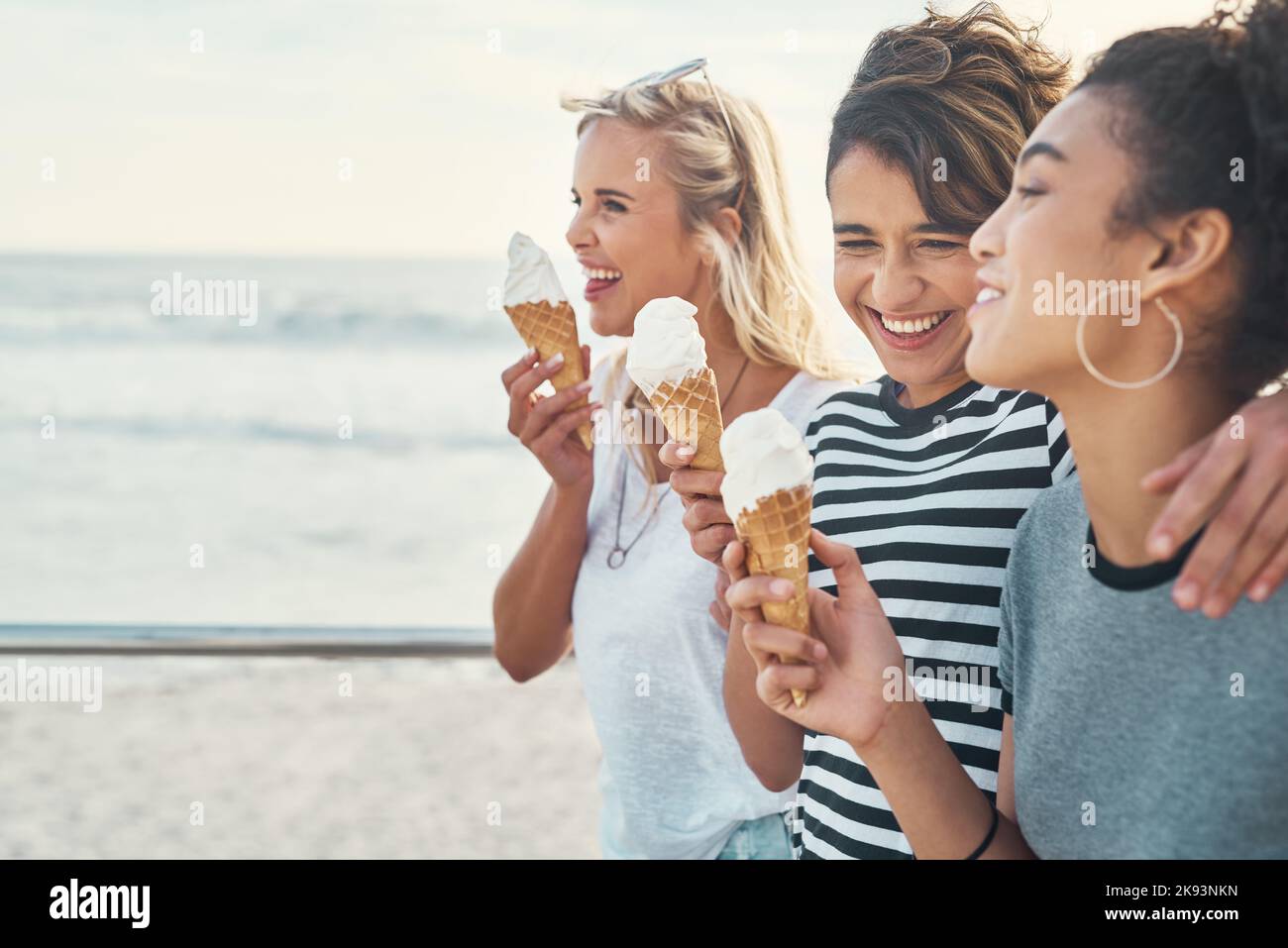 La crème glacée fait tout mieux. Trois amis mangent de la glace pendant qu'ils sont sur la promenade. Banque D'Images