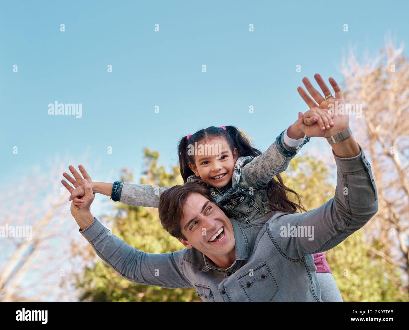 Le temps est précieux, passez-le avec ceux qui sont précieux. Une adorable petite fille qui profite d'une promenade en pigeyback avec son père au parc. Banque D'Images