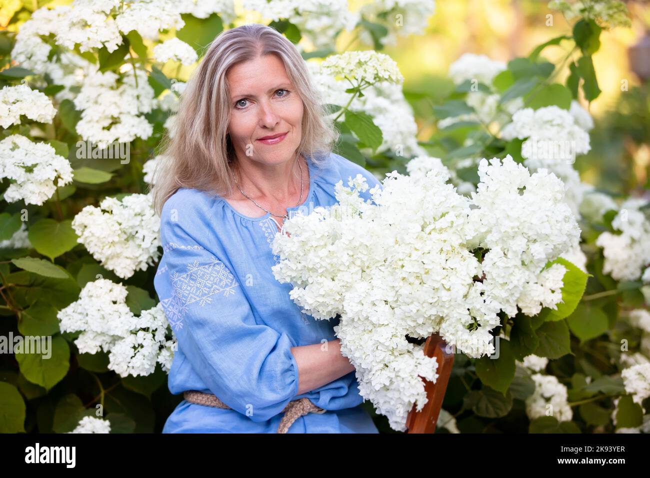 Belle femme âgée avec un bouquet de fleurs. Femme souriante dans son jardin. Banque D'Images