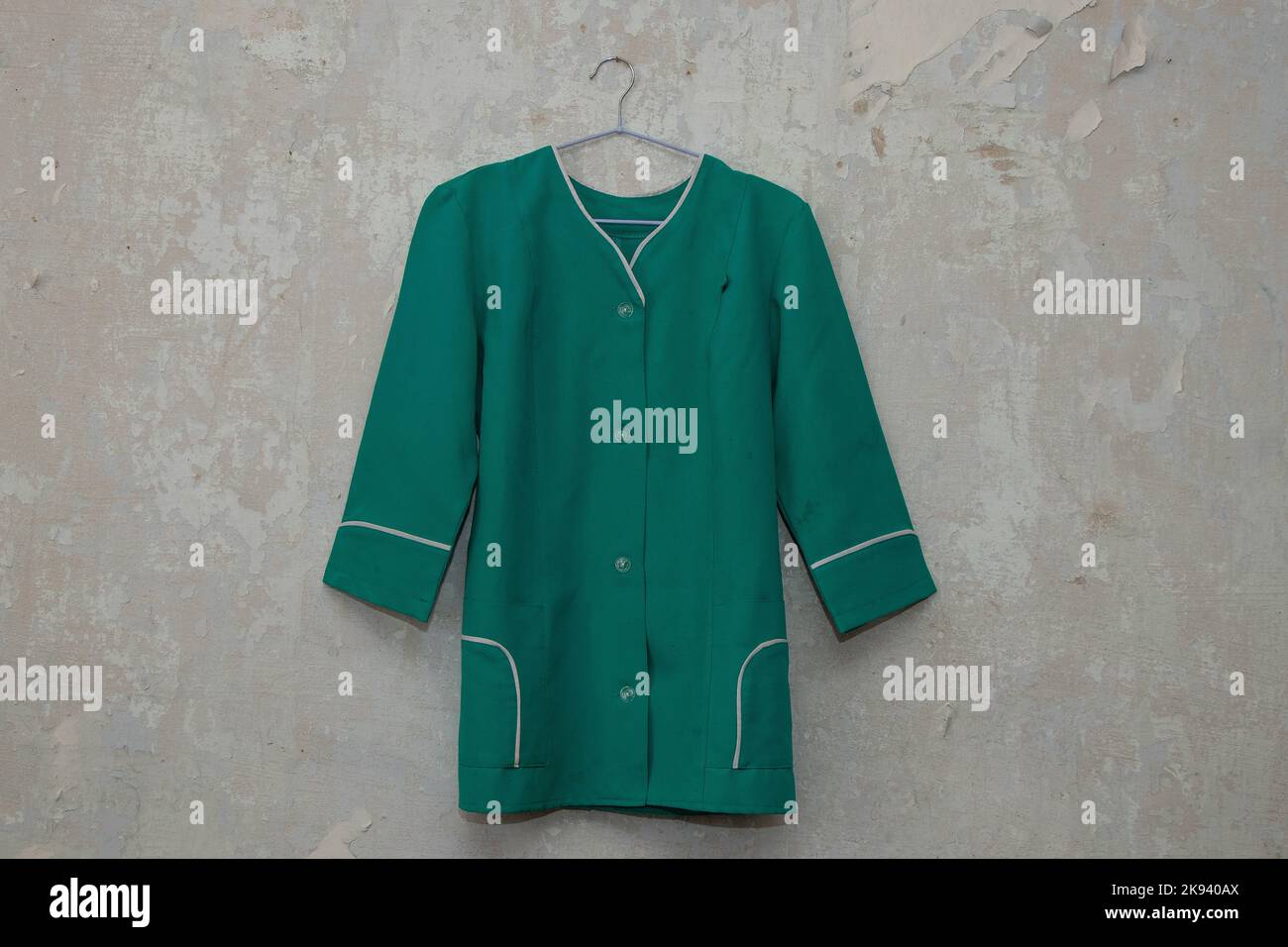 uniforme médical d'une infirmière accrochée à un cintre sur un mur blanc à la maison Banque D'Images