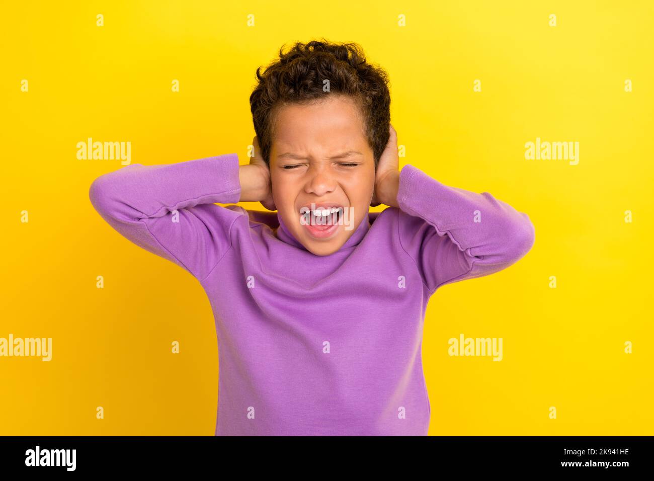 Photo portrait de mignon petit garçon fermé yeux couvrir les oreilles éviter le bruit ignorer porter tendance violet look isolé sur fond jaune Banque D'Images