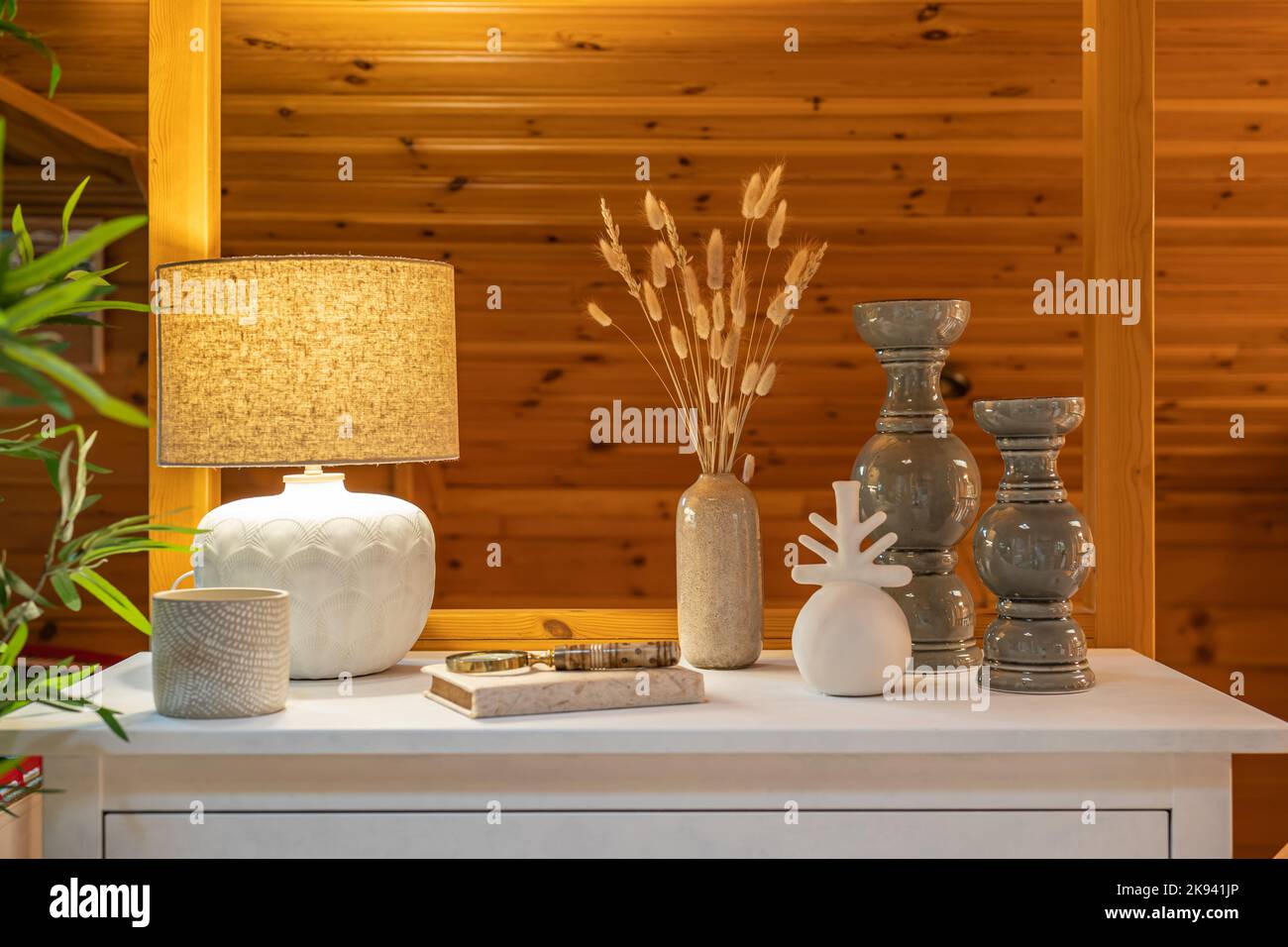 Concept de décoration d'intérieur. Vases divers avec blé sec, une lampe jaune sur une commode blanche dans un intérieur de pièce en bois. Banque D'Images