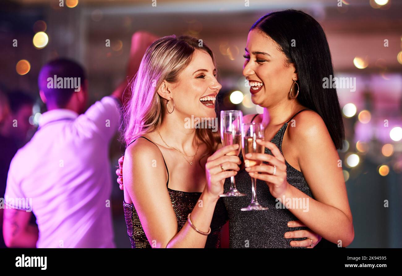 Nous y retournons sans hésiter. Deux jeunes femmes gaies ont un toast festif avec des boissons dans un bar le soir. Banque D'Images
