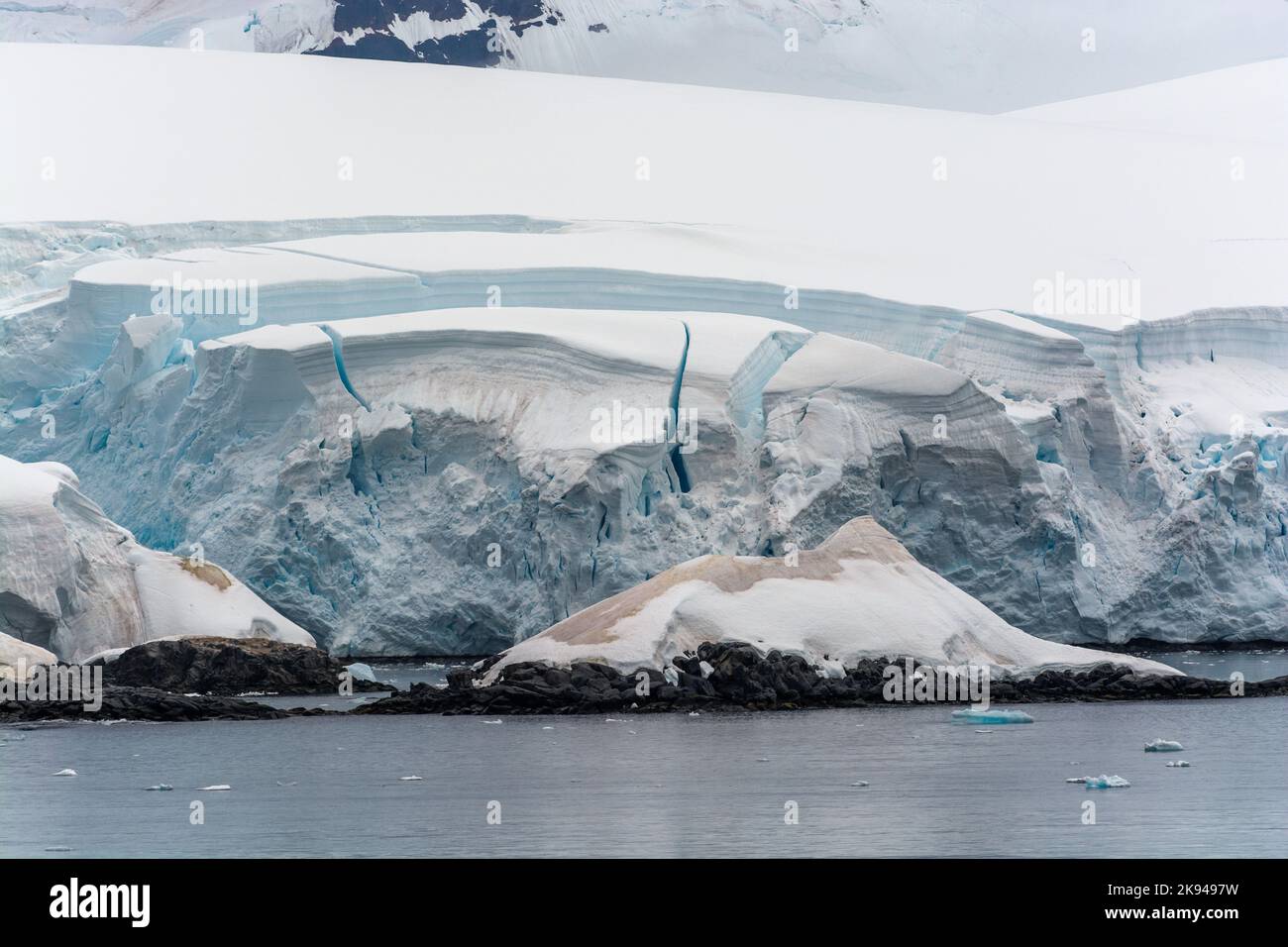 fissures dans la glace de falaise prêtes à se briser derrière des îles enneigées. canal schollaert. péninsule antarctique. antarctique Banque D'Images