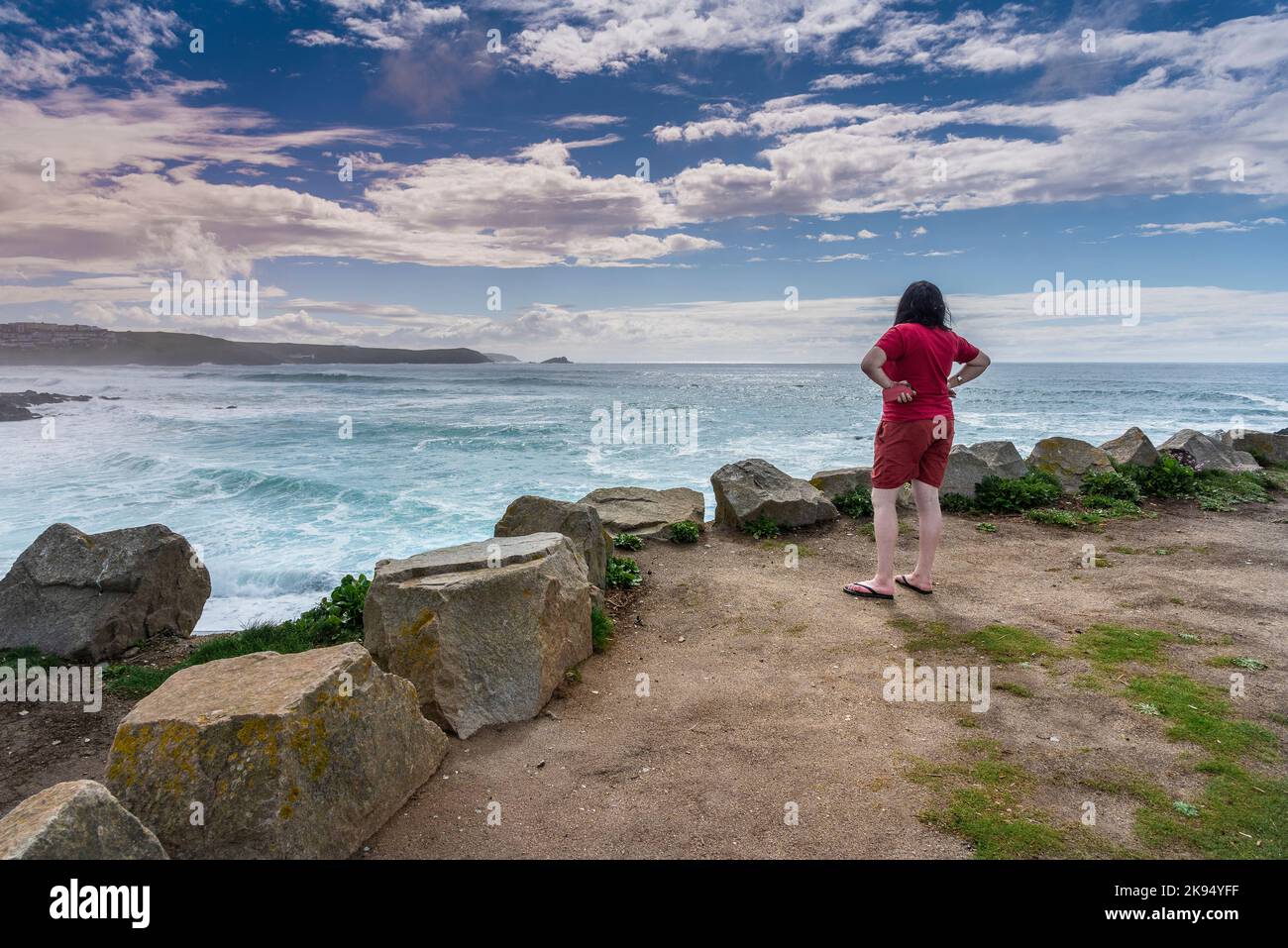 Une femme en vacances debout et regardant sur Fistral Bay à Newquay, en Cornouailles, au Royaume-Uni. Banque D'Images