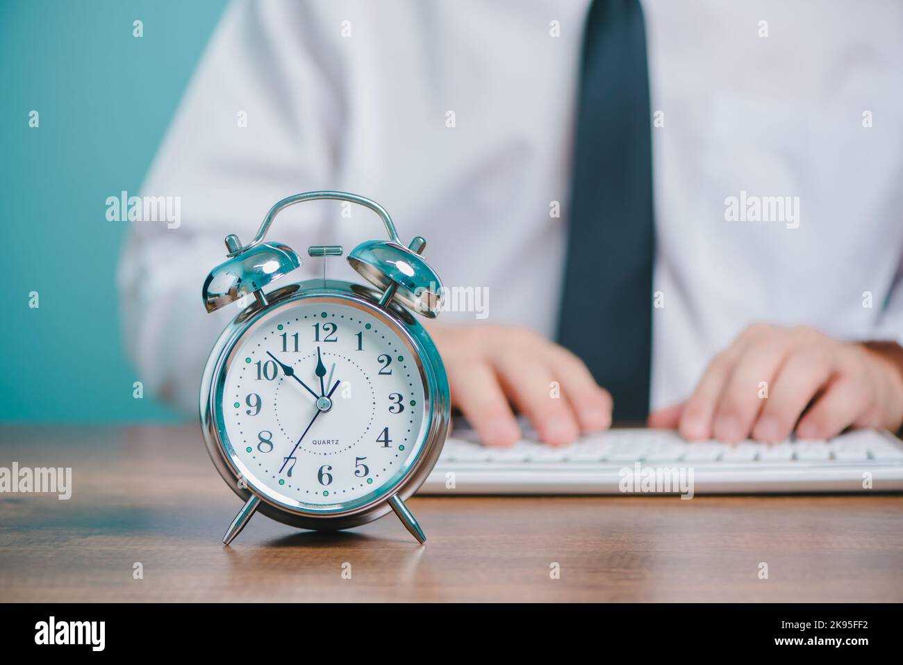 Concept de temps de travail pour les professionnels, homme d'affaires travaillant et tapant sur un ordinateur portable avec horloge sur le bureau. Banque D'Images