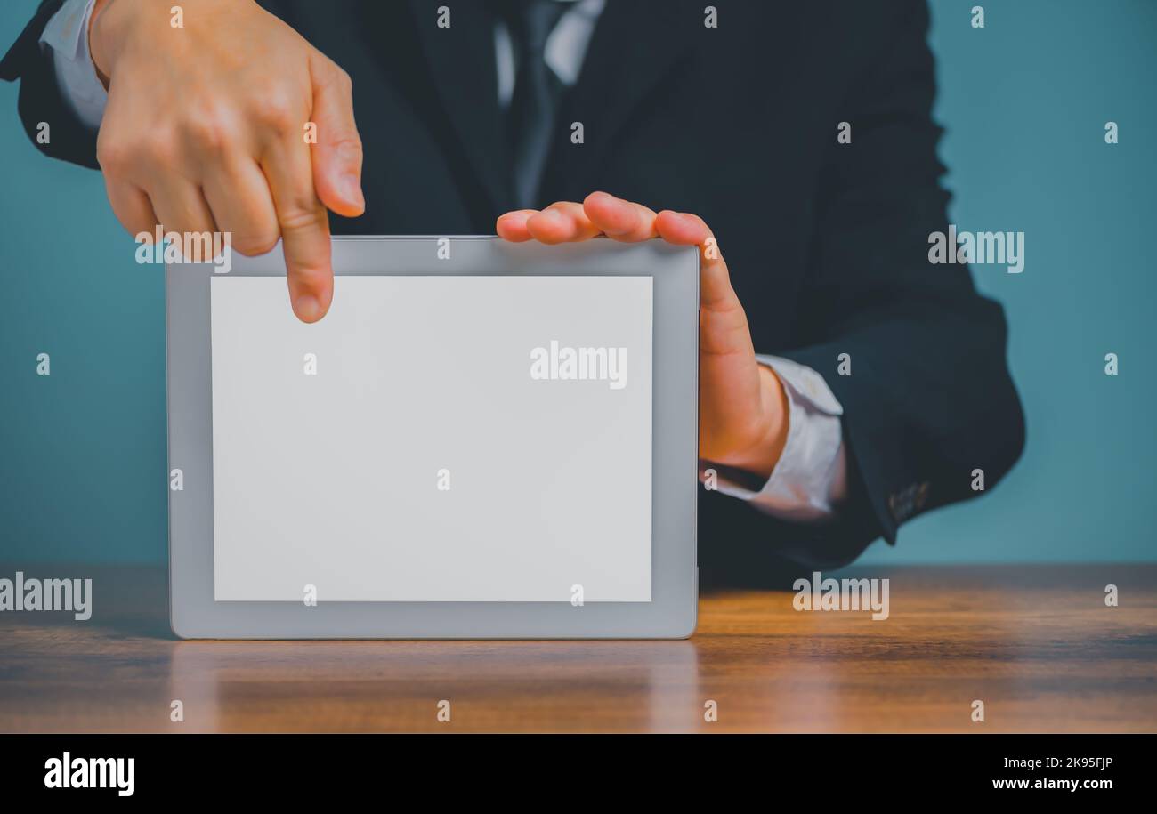Homme d'affaires tenant et pointant sur une tablette numérique sur le bureau avec un arrière-plan blanc isolé et un espace de copie. Banque D'Images