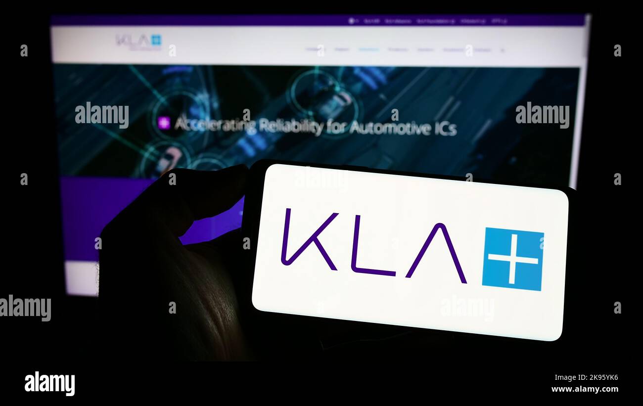 Personne tenant un smartphone avec le logo de la société américaine de semi-conducteurs KLA Corporation à l'écran devant le site Web. Mise au point sur l'affichage du téléphone. Banque D'Images