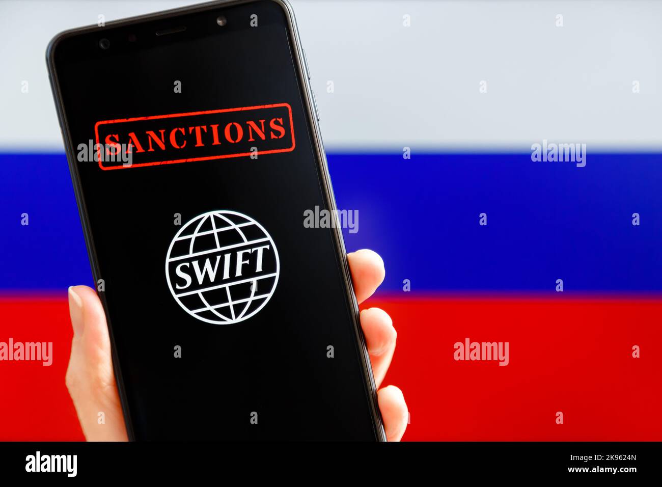 Ukraine, Kiev - février 23 2022 : portable avec logo SWIFT, sanctions et drapeau russe en arrière-plan. Sanctions contre la Russie, déconnexion du concept SWIFT. Banque D'Images