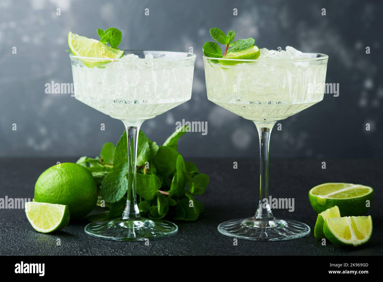 Cocktail de Margarita avec citron vert, tequila, menthe et glace sur table sombre avec rétroéclairage incroyable, espace de copie. Margarita classique ou cocktail Daiquiry. Carte à barres Banque D'Images