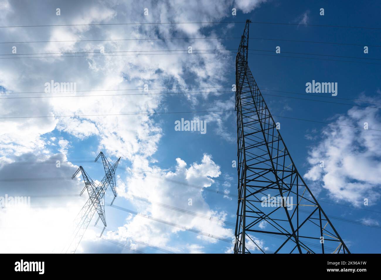 Pylône d'électricité pour la transmission et le transfert de courant de haute tension à travers des paysages naturels devant un ciel nuageux Banque D'Images