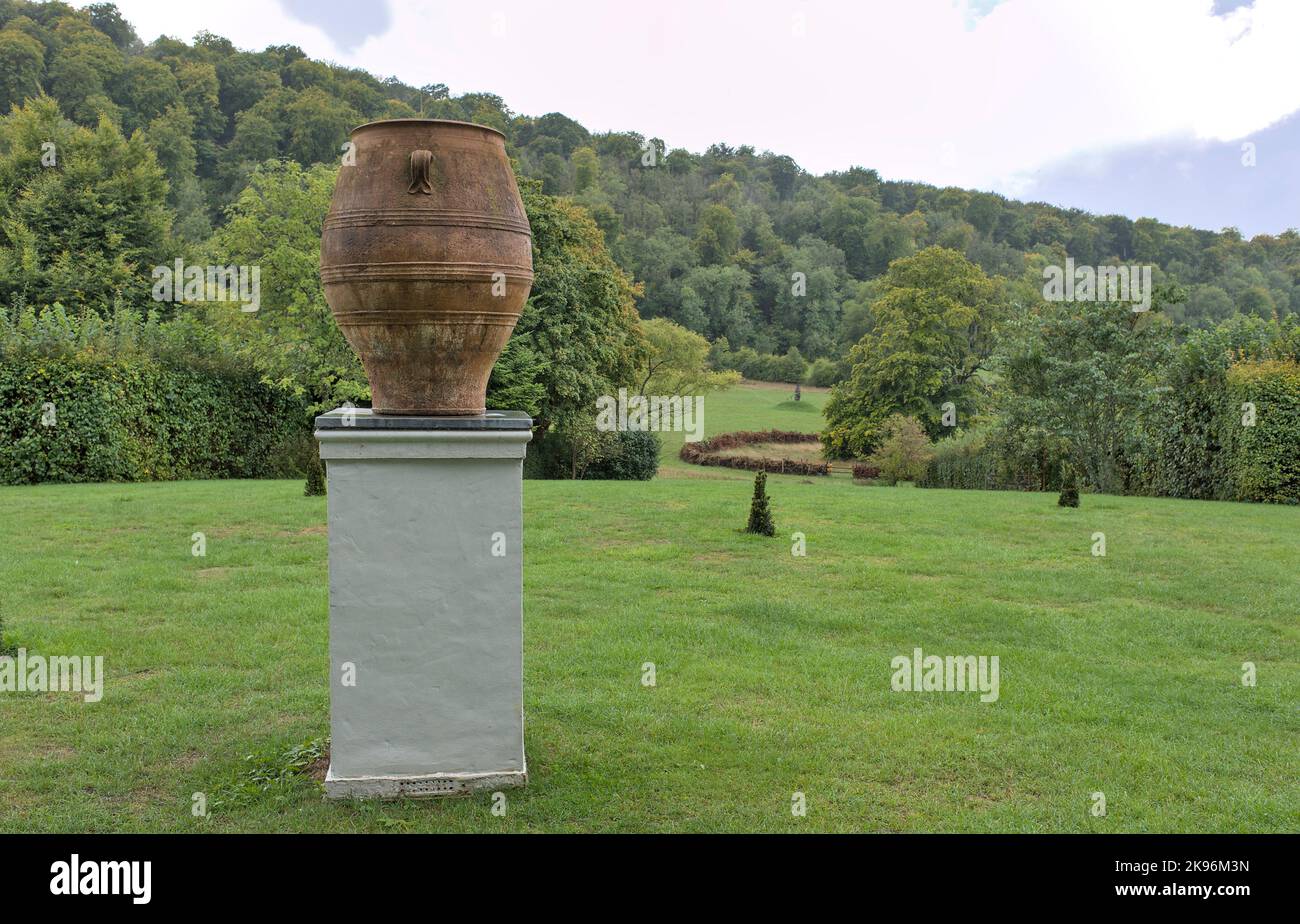 Grande urne en terre cuite sur plinthe blanche devant le parc paysager et les arbres des jardins Gilbert Whites Hampshire Banque D'Images