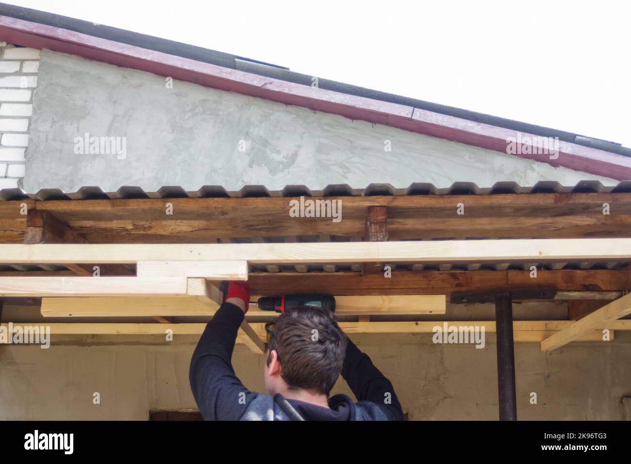 Déconcentrer le travailleur à l'aide d'une perceuse travaillant sur la construction de la maison de cadre en bois et du toit. Peu de travaux de construction résidentielle. Etagère en bois fixe homme avec Banque D'Images