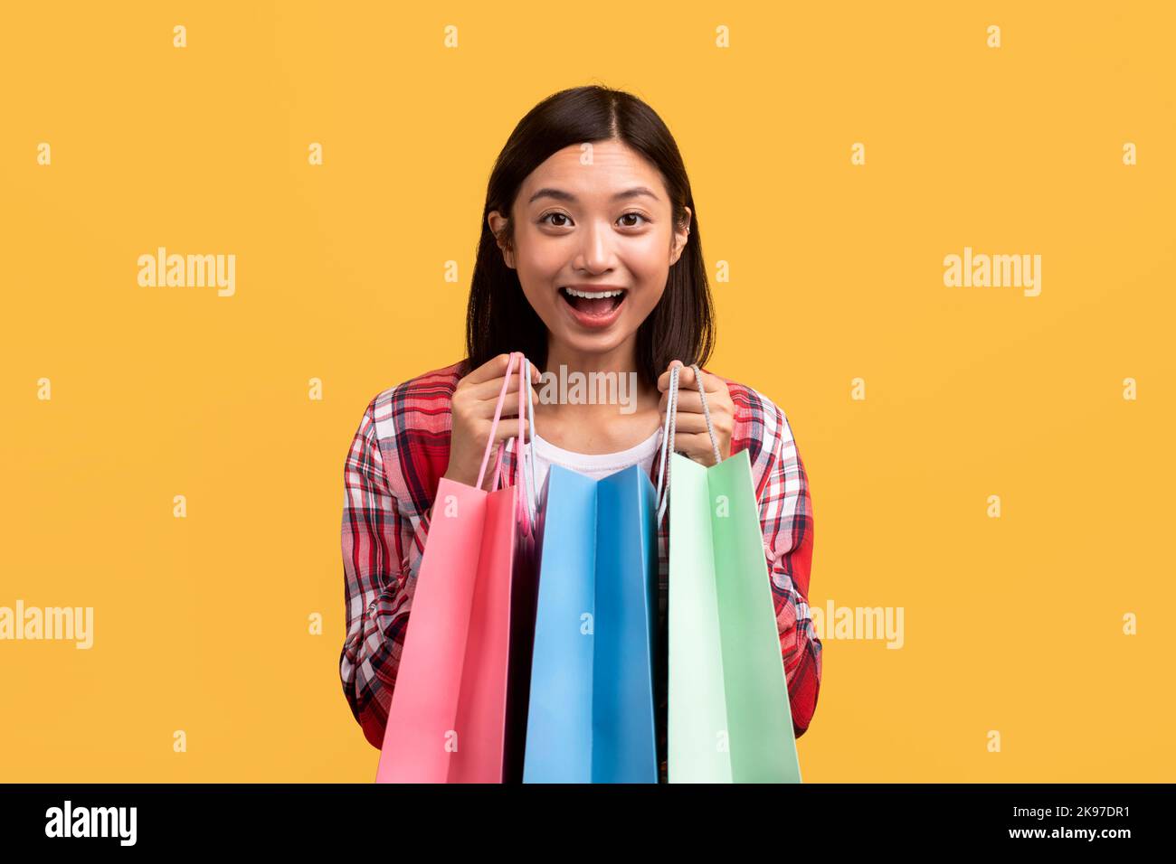 Client satisfait. Une dame chinoise pleine de joie ouvre des sacs de shopping colorés, heureuse de ses achats Banque D'Images