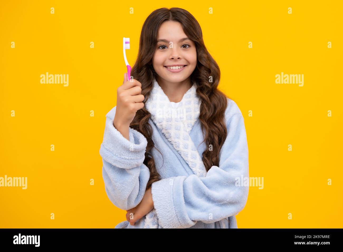 Portrait de la jeune fille caucasienne tient une brosse à dents se brossant ses dents, routine du matin, hygiène dentaire, isolé sur fond jaune. Banque D'Images