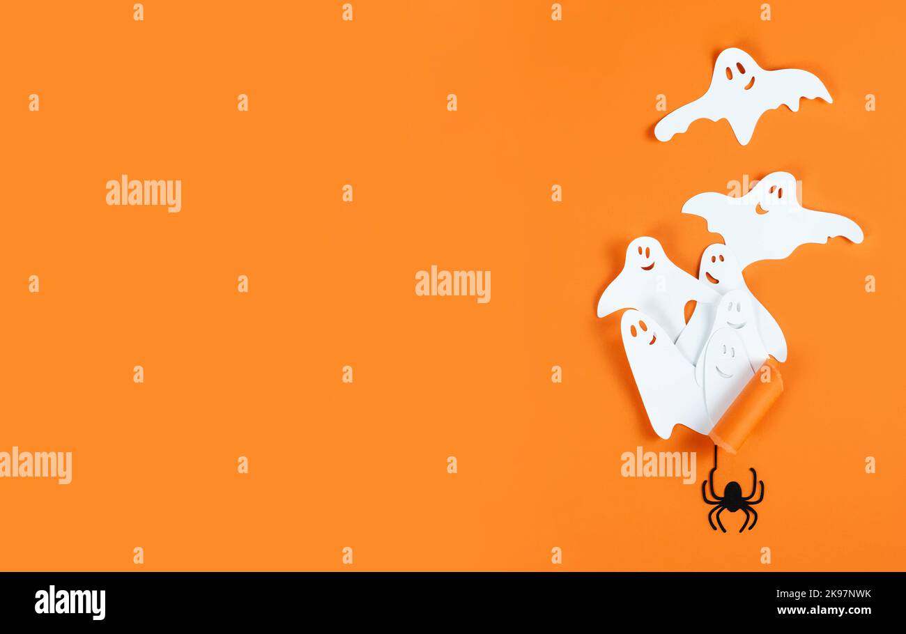 Bannière Halloween avec fantômes en papier et araignée sur fond orange avec espace de copie. Banque D'Images