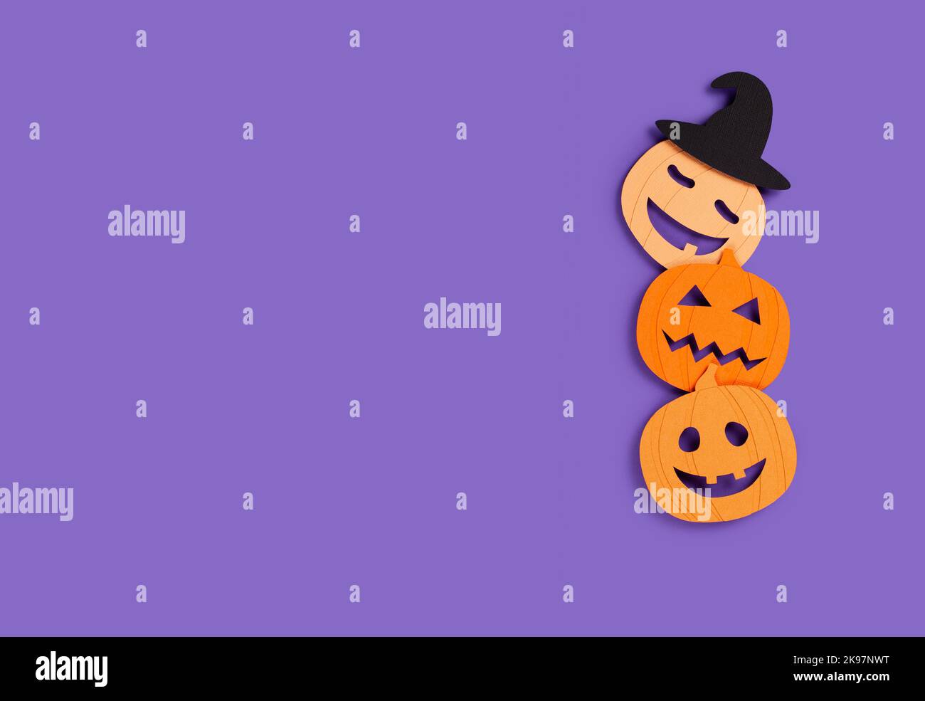 Bannière Halloween avec trois citrouilles en papier sur fond violet. Banque D'Images