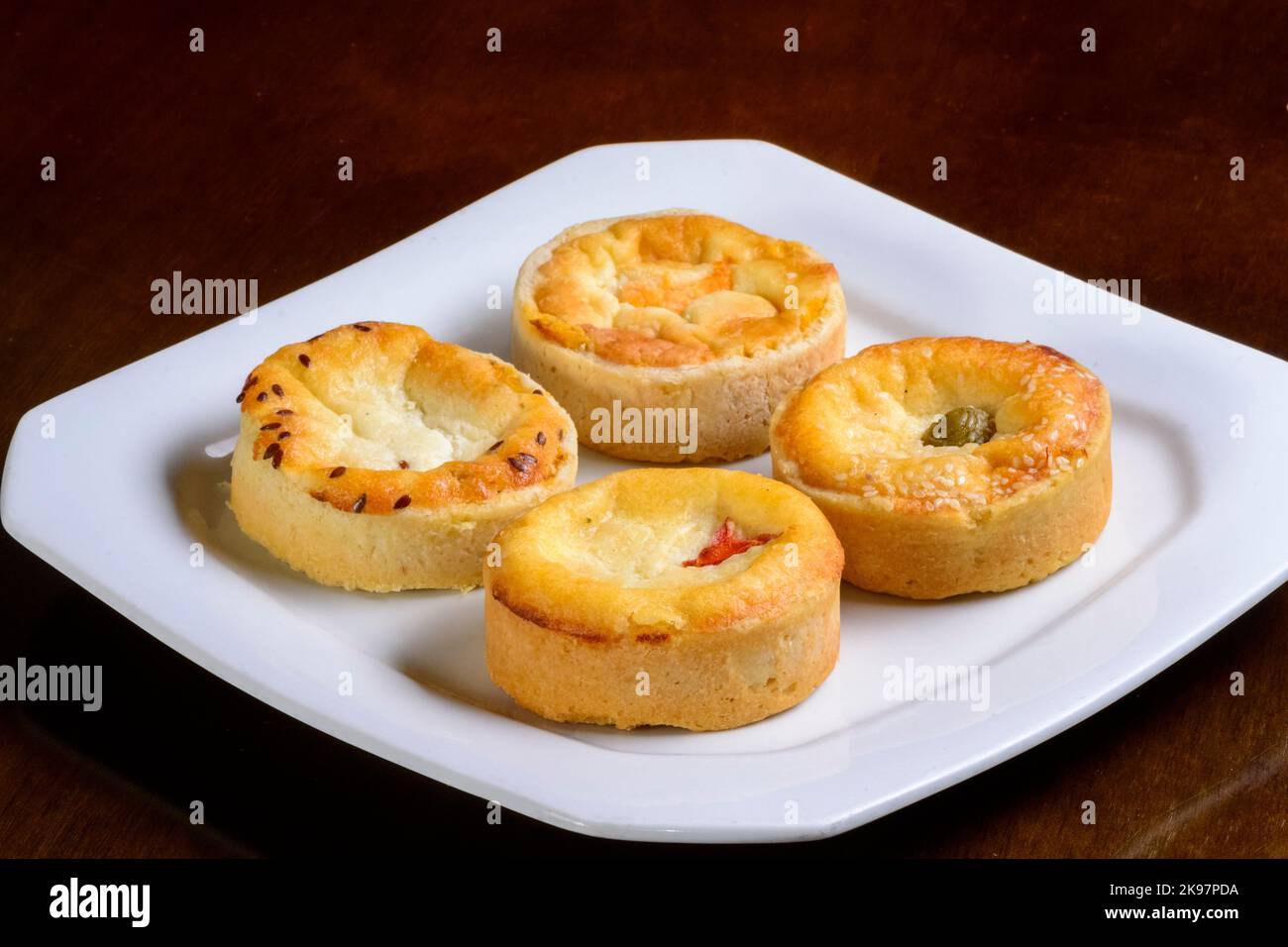 Mini quiches en-cas de saveurs variées sur une assiette blanche. Banque D'Images