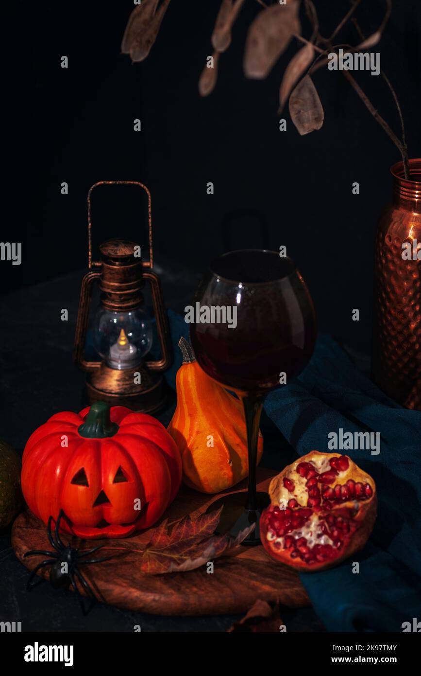 Halloween festive mise en page avec Jack-O-Lantern, citrouilles, lanterne vintage, vin dans un verre et araignée sur planche à découper en bois. Arrière-plan noir. Automne Banque D'Images