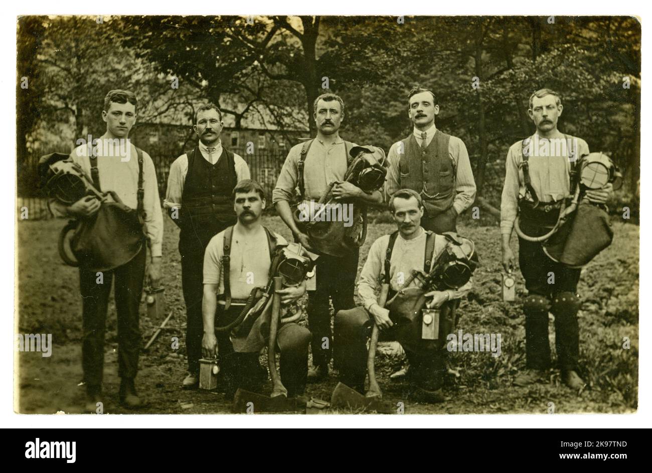 Carte postale originale du début des années 1900 de l'équipe de sauvetage de mines de charbon avec haches et appareil respiratoire de maintien sous forme de casques de fumée Draeger /Drager avec sac respiratoire attaché recouvert d'un rabat en cuir, avec lampes, genouillères de protection et une scie (en premier plan) ils étaient bien équipés pour répondre en cas de catastrophe. Vers 1919, Royaume-Uni Banque D'Images