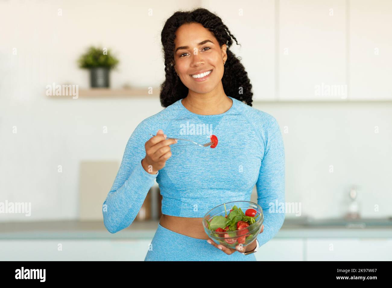 Concept de régime et de perte de poids. Bonne tenue femme noire dans les  vêtements de sport manger de la salade de légumes frais à l'intérieur de la  cuisine Photo Stock -