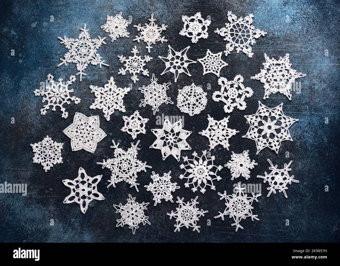 Vue de dessus des étoiles en coton blanc et des flocons de neige sur fond bleu foncé. Décoration de Noël faite à la main ou petit cadeau. Banque D'Images
