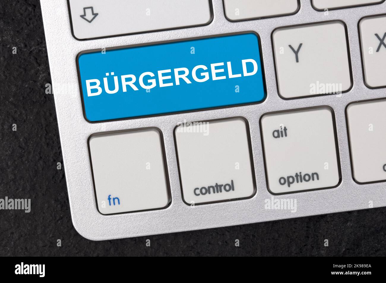 Clavier avec le mot allemand Bürgergeld ( engl. Citizen Money) isolé sur fond sombre. Nouveau système d'aide financière en Allemagne. Concept de soutien social. Banque D'Images
