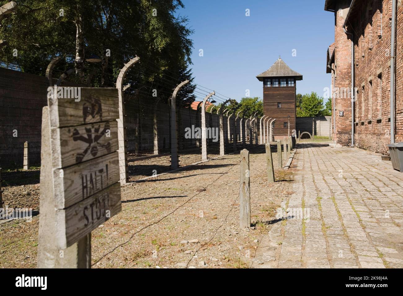 Clôtures électrifiées à barbwire et tour de garde dans l'ancien camp de concentration nazi d'Auschwitz, Auschwitz, Pologne. Banque D'Images