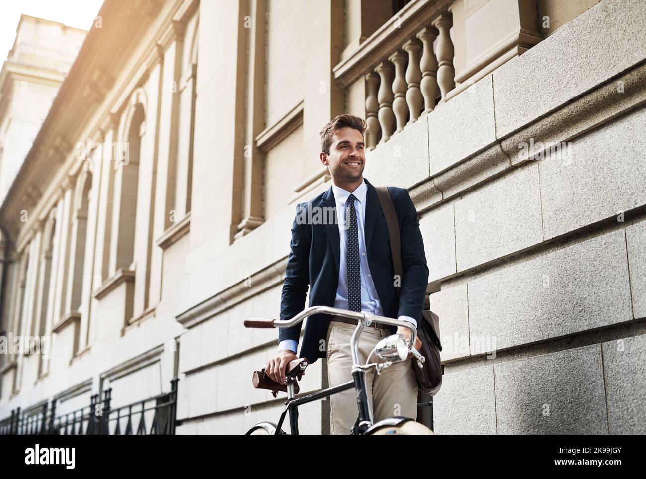 Pas trop loin pour aller de l'avant. Un beau jeune homme d'affaires poussant son vélo tout en se rendant au travail le matin. Banque D'Images