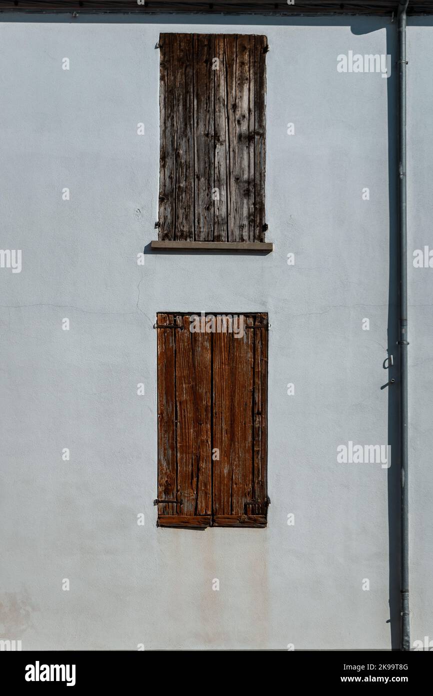 Façade blanche d'un ancien bâtiment avec deux fenêtres en bois recouvertes de parasols Banque D'Images