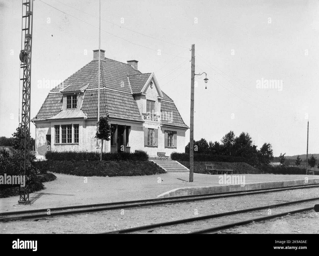 Vielée avec de belles fenêtres, doublure, trappes et piliers gris bleu. Raccords en zinc au plafond, moulures gris-blanc, toits carrelés rouges, cheminées jaunes grisâtres. Signe gris -blanc avec style noir et ombrage vert. Banque D'Images